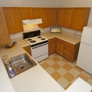 A compact kitchen with wooden cabinets and standard appliances.
