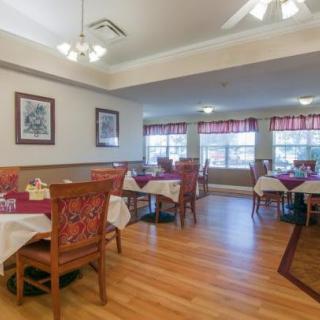 A cozy dining room with neatly arranged tables and chairs on a wooden floor.