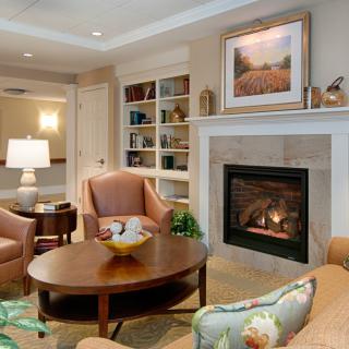 A cozy living room with a fireplace, armchairs, and a bookshelf.