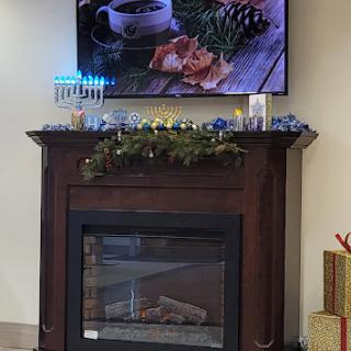 A cozy setting featuring a decorated fireplace with holiday decor and a TV displaying a warm beverage.
