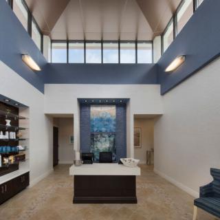 A modern lobby area with a reception desk, high ceilings, and stylish decor.