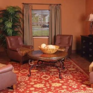 A cozy living room featuring leather chairs, an ornate rug, and a decorative wooden table.