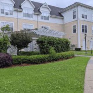 A view of a residential building with a well-maintained lawn and pathway.