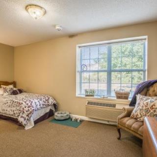 A cozy bedroom with a single bed, chair, and large window offering natural light.