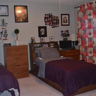 A cozy bedroom with twin beds, decorated walls, and furniture.
