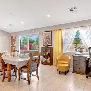 A cozy dining and office area with wooden furniture and decorative elements, featuring a window with a garden view.