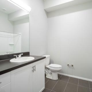 A modern, minimalist bathroom with a sink, mirror, and toilet.