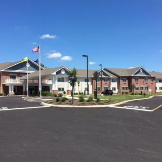 A large residential building with a well-maintained exterior, featuring flags and a clear blue sky.