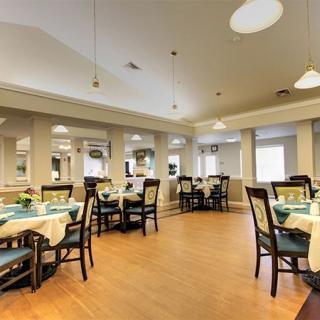 A well-lit dining area with neatly arranged tables and chairs on a wooden floor.