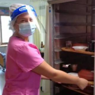 A healthcare worker in pink scrubs and protective gear working in a hospital setting.