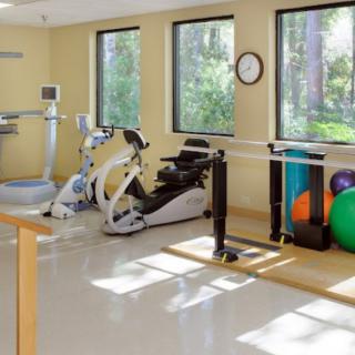 A well-equipped physical therapy and rehabilitation room with exercise machines and therapy tools.