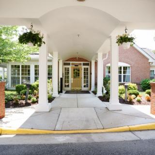A welcoming entrance to a building with a covered walkway and well-maintained landscaping.