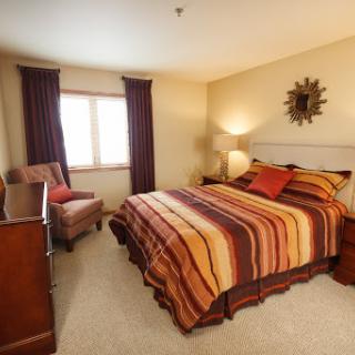 A cozy bedroom featuring a striped bedspread and warm lighting.