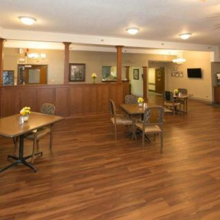 A cozy dining area with wooden floors and neatly arranged tables and chairs.