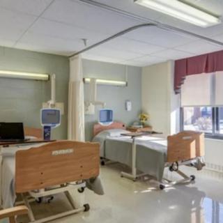 An empty hospital room with two patient beds and medical equipment.