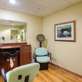 A cozy hair salon interior with chairs, a mirror, and a vintage hair dryer.