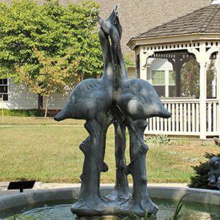 A decorative fountain featuring a bird sculpture in a garden setting.