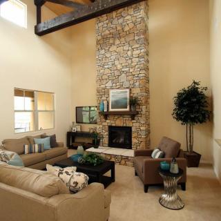 A stylish living room featuring a tall stone fireplace, comfortable seating, and elegant decor.