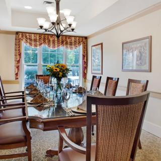 A well-decorated dining room with a set dining table, surrounded by elegant chairs and illuminated by a chandelier.