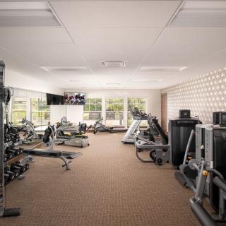 A well-equipped gym with various exercise machines, weights, and treadmills in a spacious indoor setting.