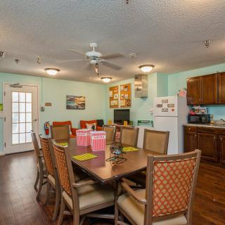 A cozy dining area adjoining a kitchen with a wooden table and chairs, decorated in warm tones.