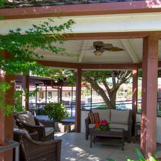 A cozy gazebo with comfortable outdoor seating surrounded by lush trees in a garden setting.