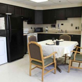 A modern kitchen with a dining area featuring a table and chairs, along with various appliances.