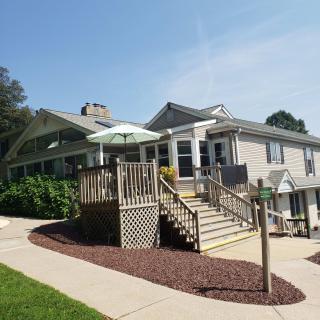 A residential house with a wooden deck and stairs leading to the entrance, featuring an outdoor umbrella.