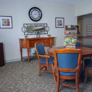 A cozy lounge area featuring a wooden table and chairs, adorned with decorative elements like a clock and mirror on the wall.