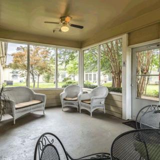 A cozy screened porch with wicker furniture and a ceiling fan, offering a relaxing indoor-outdoor space.
