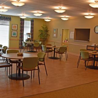 An empty dining area with neatly arranged tables and chairs, illuminated by overhead lights.