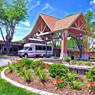 A welcoming entrance to a hospitality facility surrounded by lush greenery and vibrant flowers.