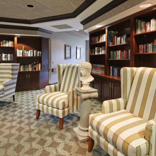 A cozy library reading area with striped armchairs and bookshelves filled with books.