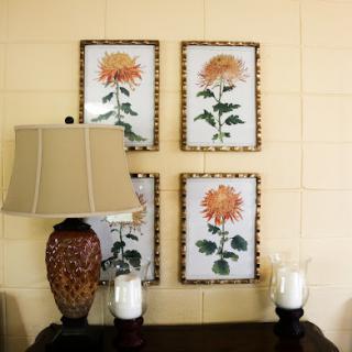 A cozy corner featuring floral wall art, an elegant lamp, and candles.