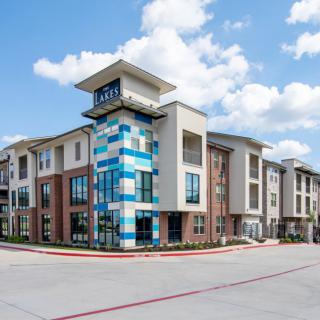 A modern apartment building with colorful accents under a partly cloudy sky.