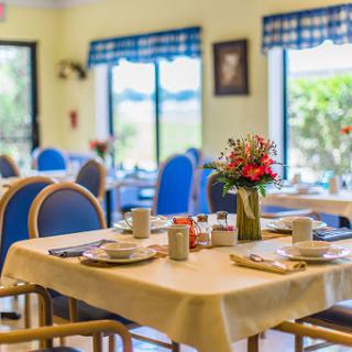 A cozy dining area set up for a meal, featuring tables adorned with dishes and a flower centerpiece.
