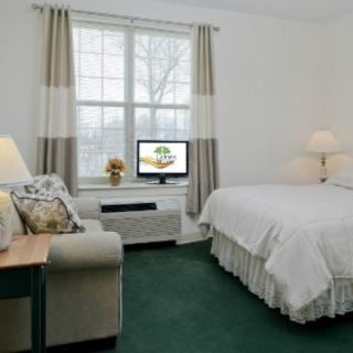 A cozy hotel room with a large bed, sofa, and a television near the window.
