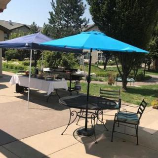 Outdoor patio setup with tables, chairs, and umbrellas on a sunny day.