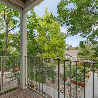 A serene view from a balcony overlooking lush greenery and a residential neighborhood.