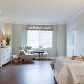 A modern and spacious bedroom with natural lighting, featuring elegant decor and wooden flooring.