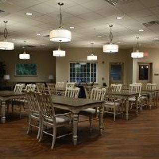 A spacious and modern dining area with neatly arranged tables and chairs under soft lighting.