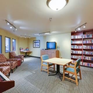 A cozy lounge area featuring comfortable seating, a television, and shelves filled with books.