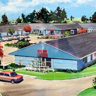 A picturesque view of a vintage-style building complex surrounded by lush greenery and parked cars.