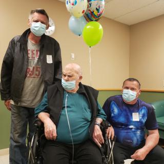 A family gathering in a healthcare setting, celebrating together with balloons.