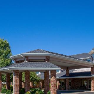 A modern building entrance with a canopy and brick pillars against a clear blue sky.