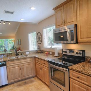 A modern kitchen featuring stainless steel appliances, wood cabinets, and granite countertops.