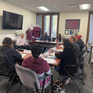 A group of individuals engaged in a discussion around a conference table, focusing on collaboration and teamwork.