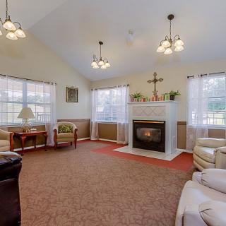 A cozy living room with a fireplace, multiple seating options, and ample natural light from large windows.