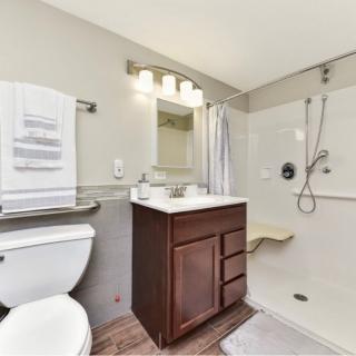 A modern bathroom with a shower, sink, and toilet.