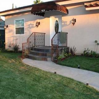 A welcoming entrance to a house with a garden pathway and awning.